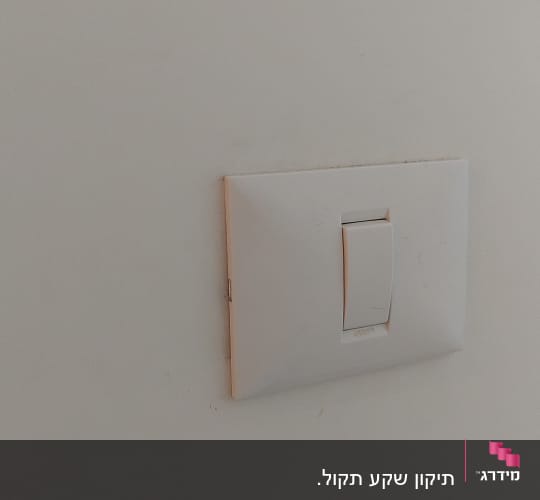 מתג חשמל לבן על קיר לבן